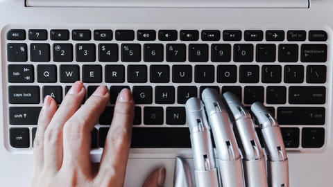 robot hands and human hands on keyboard
