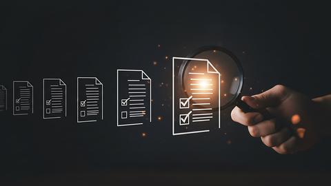 hand using magnifying glass to inspect digital checklist icons