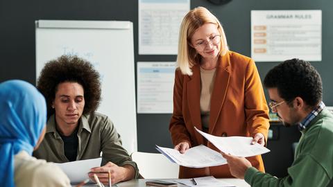 Diversified gathering of adults reviewing paperwork in a classroom
