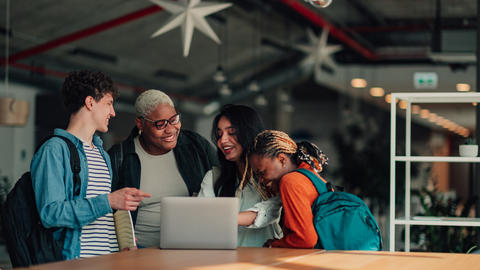 four people looking at a laptop