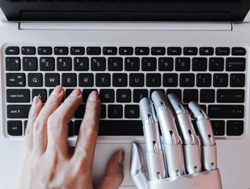 robot hands and human hands on keyboard