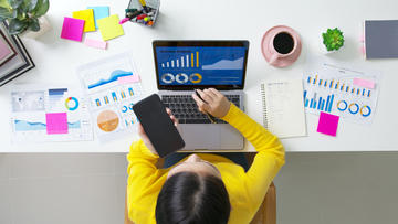above top desk of person working on laptop