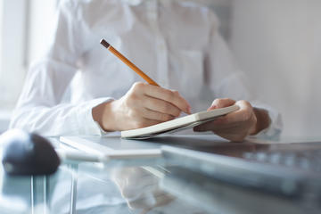 hand using a pencil noting on notepad