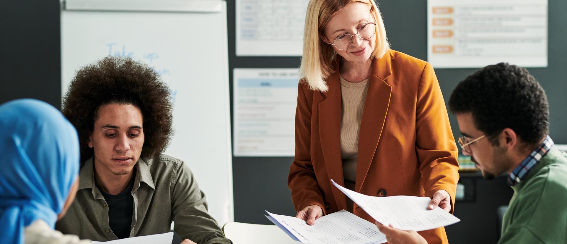 Diversified gathering of adults reviewing paperwork in a classroom