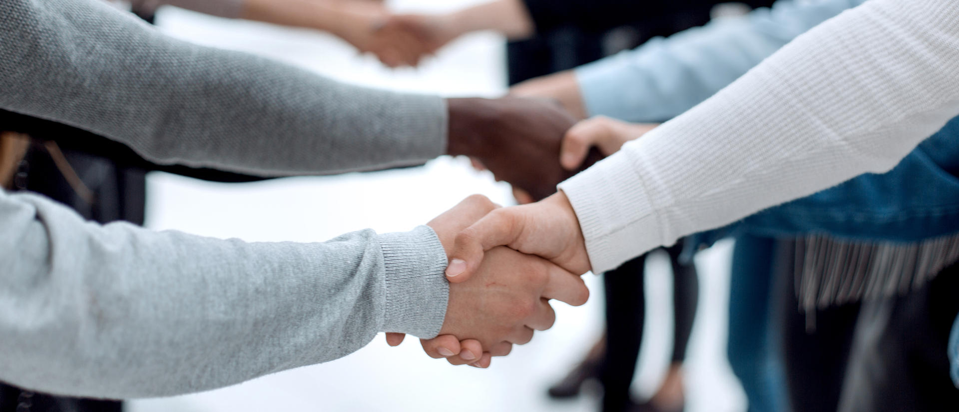 diverse young people shaking hands with each other