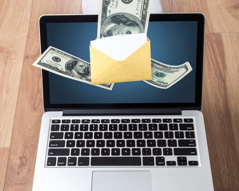 laptop showing an envelope on the screen with dollar bills appearing to float out of screen